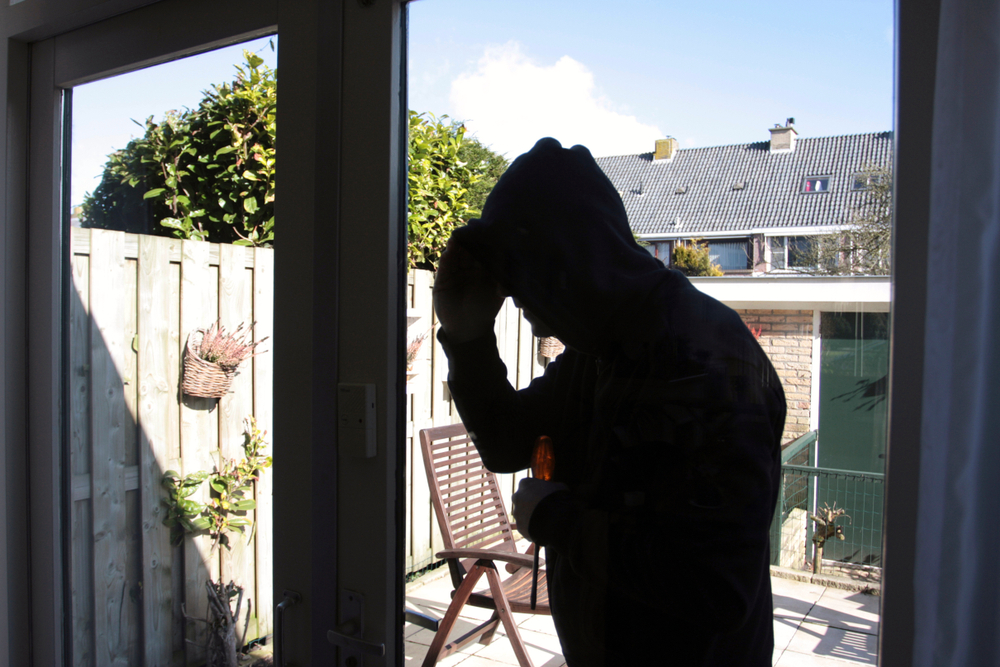 thief spying inside a house from the pool area looking for a way in